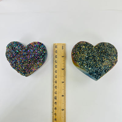 Rainbow titanium heart next to a ruler for size reference 