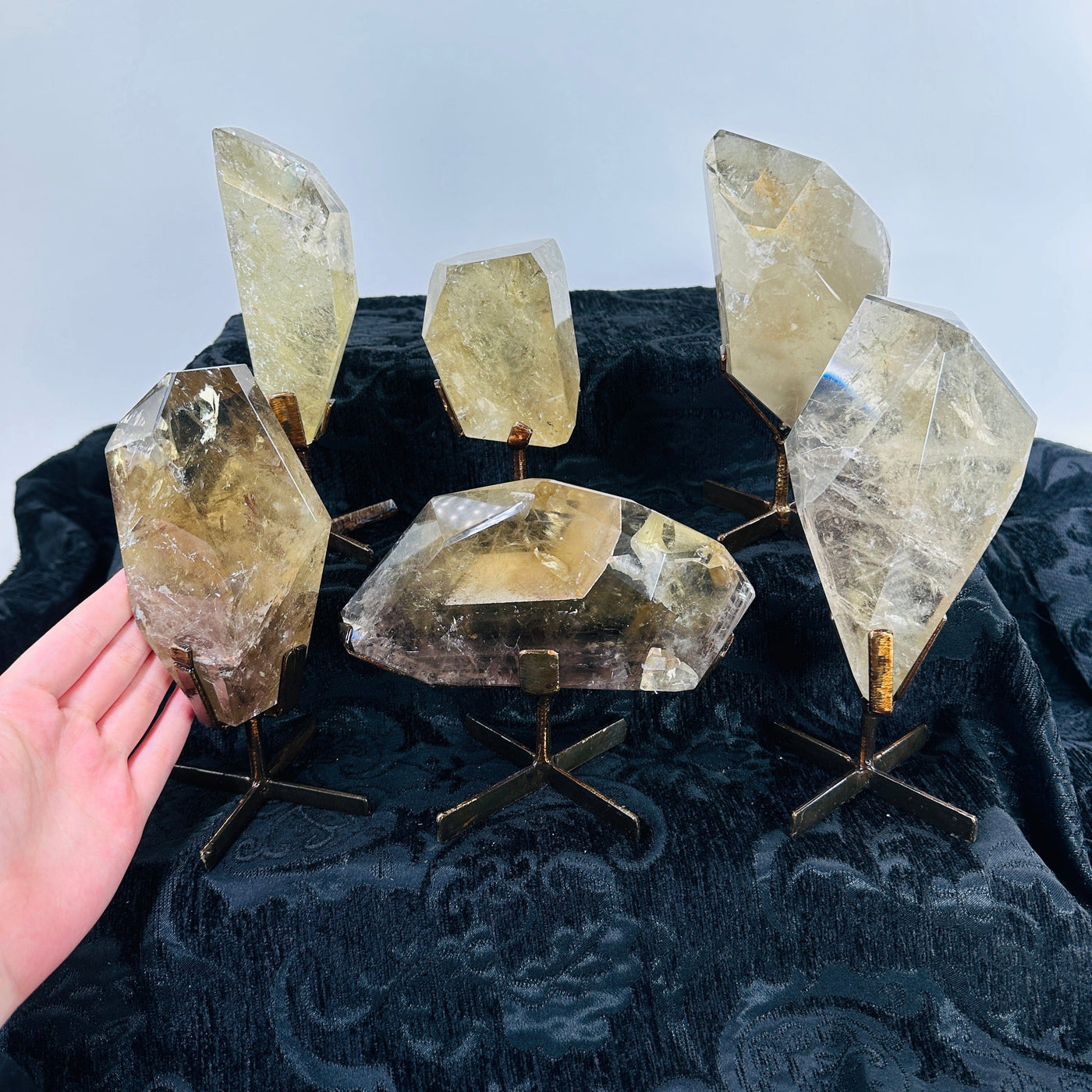 hand next to natural citrine on metal stands
