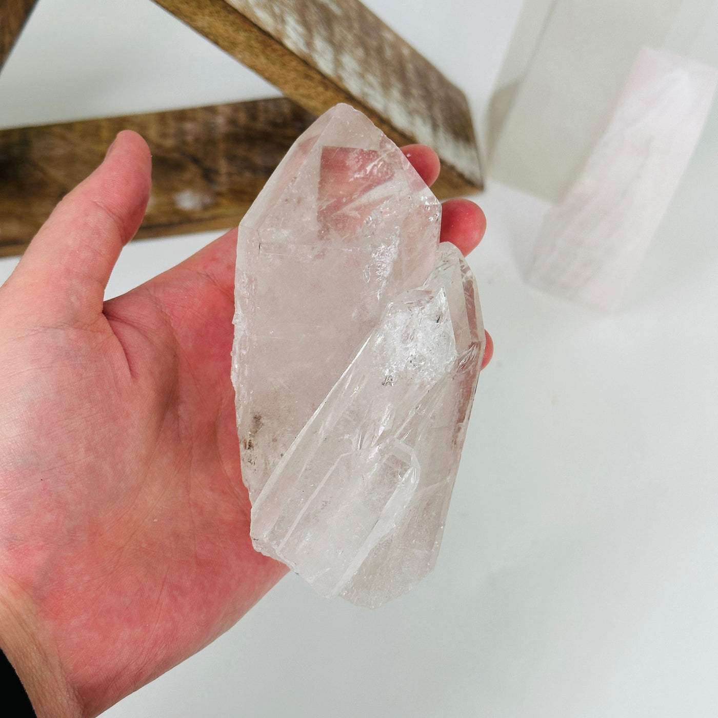 hand holding up crystal quartz cluster with decorations in the background