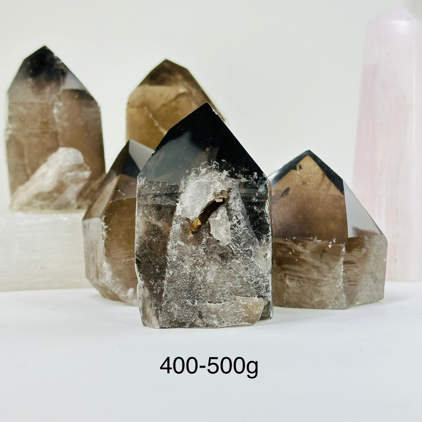 400-500g smoky quartz semi polished point with decorations in the background