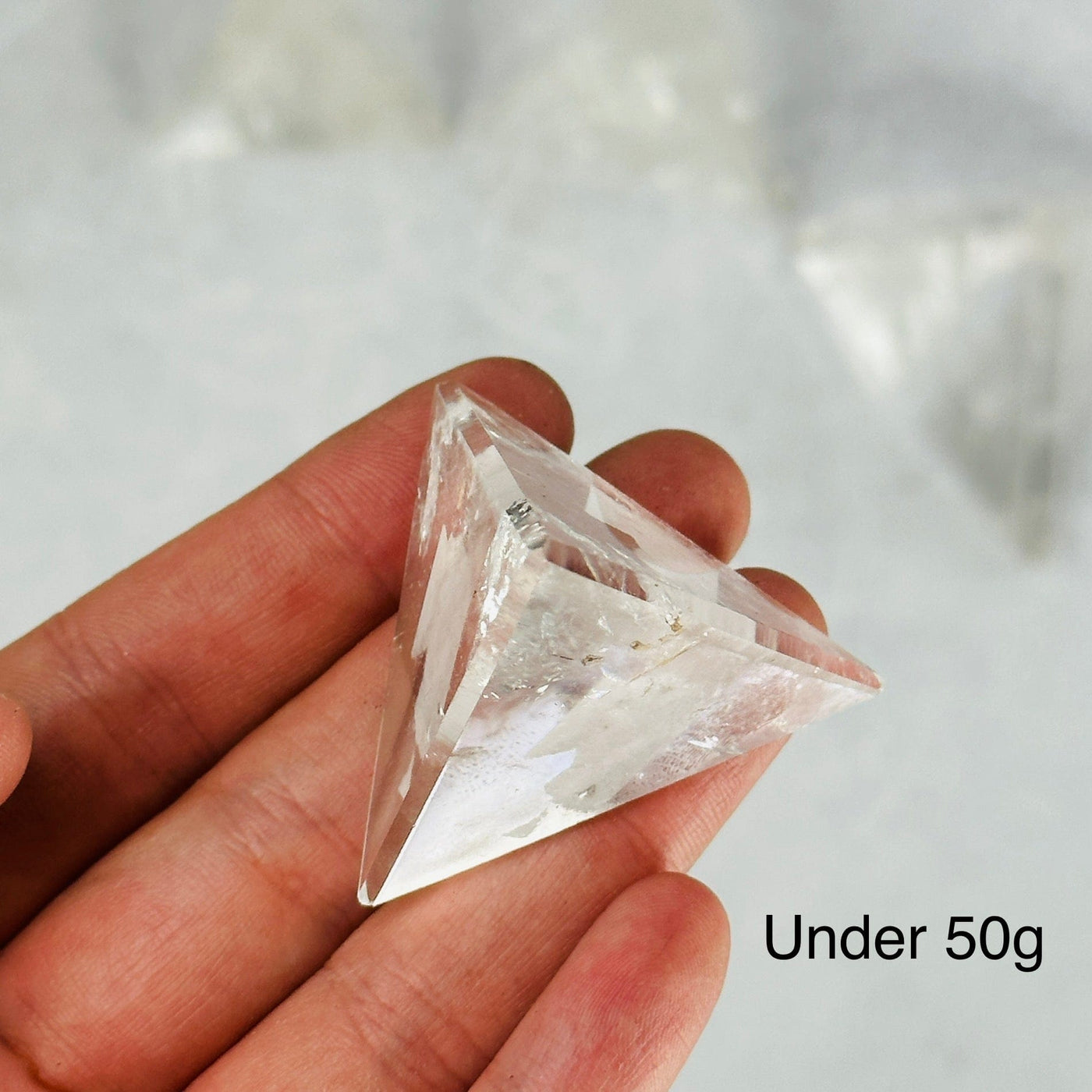 hand holding up under 50g crystal quartz pyramid