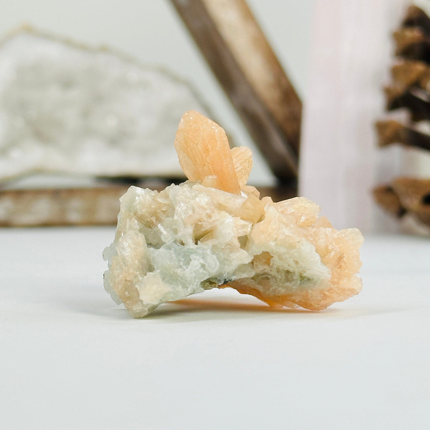 peach apophyllite cluster with decorations in the background