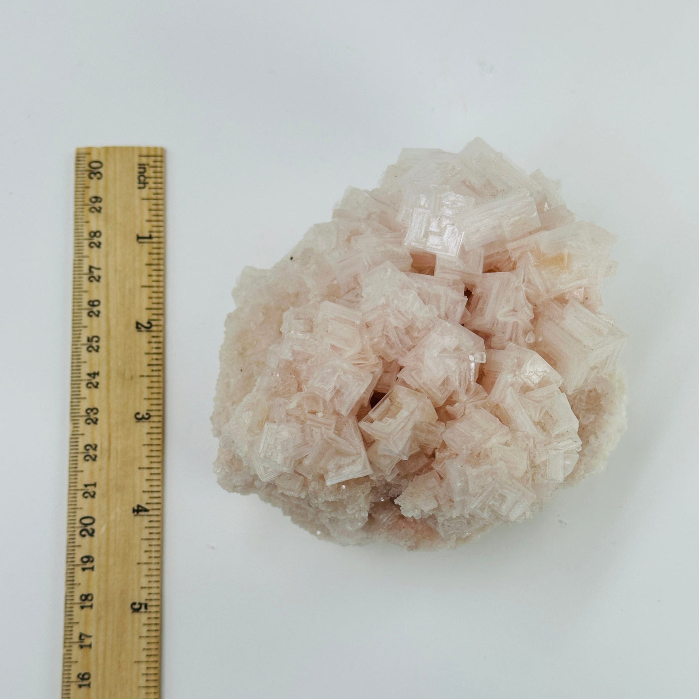 pink halite cluster next to a ruler for size reference