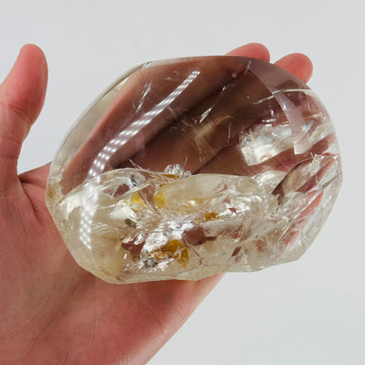 hand holding up crystal quartz with inclusions 