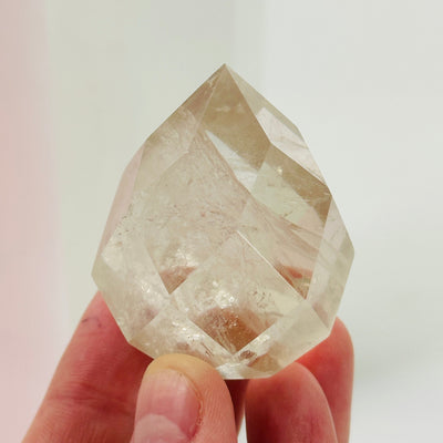 fingers holding up citrine faceted point