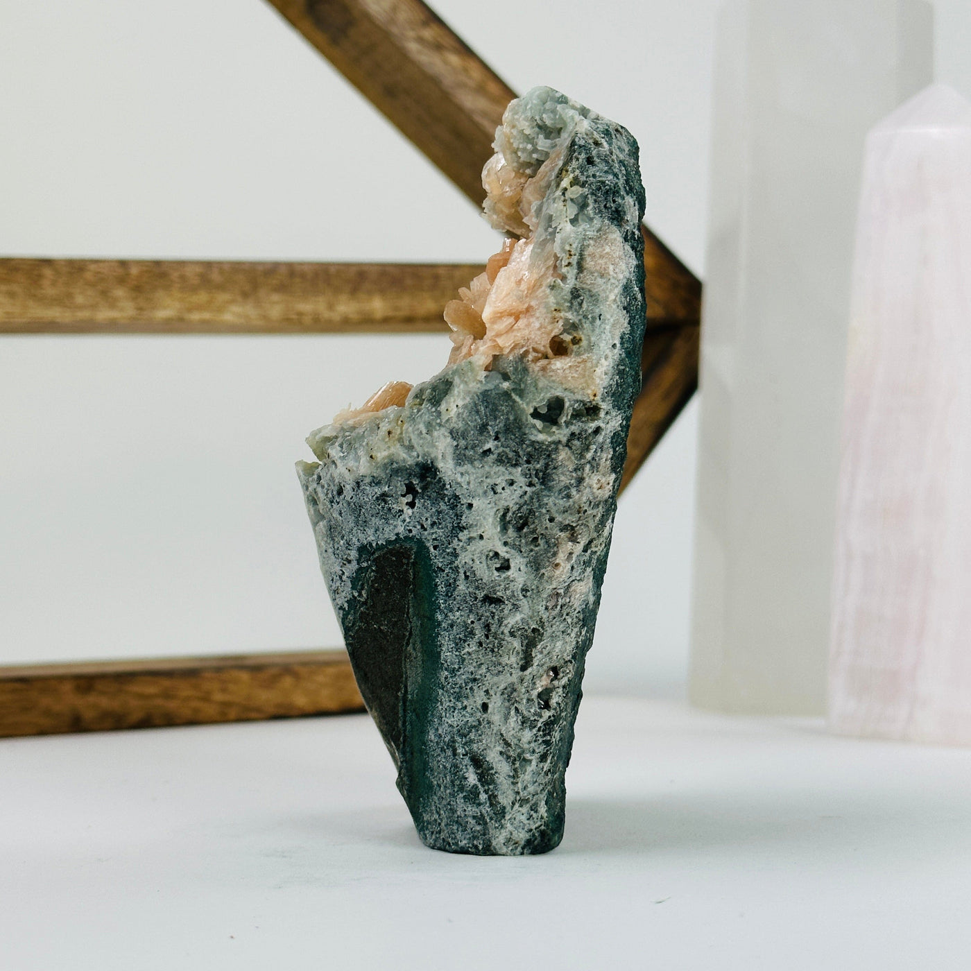 peach stilbite with apophyllite cut base with decorations in the background