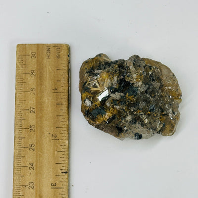 rutilated smokey quartz next to a ruler for size reference
