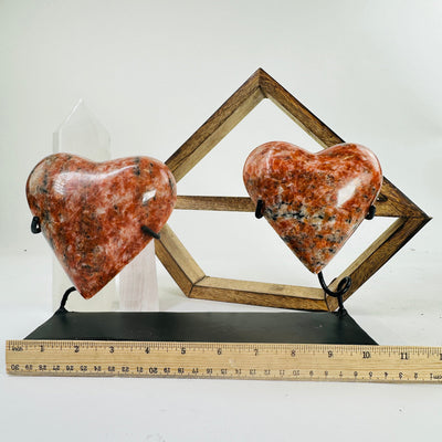 Orchid calcite hearts on stand next to a ruler for size reference