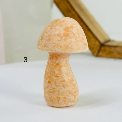 peach calcite mushroom with decorations in the background