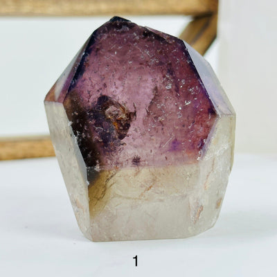 ametrine polished point with decorations in the background