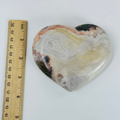 pink amethyst heart next to a ruler for size reference