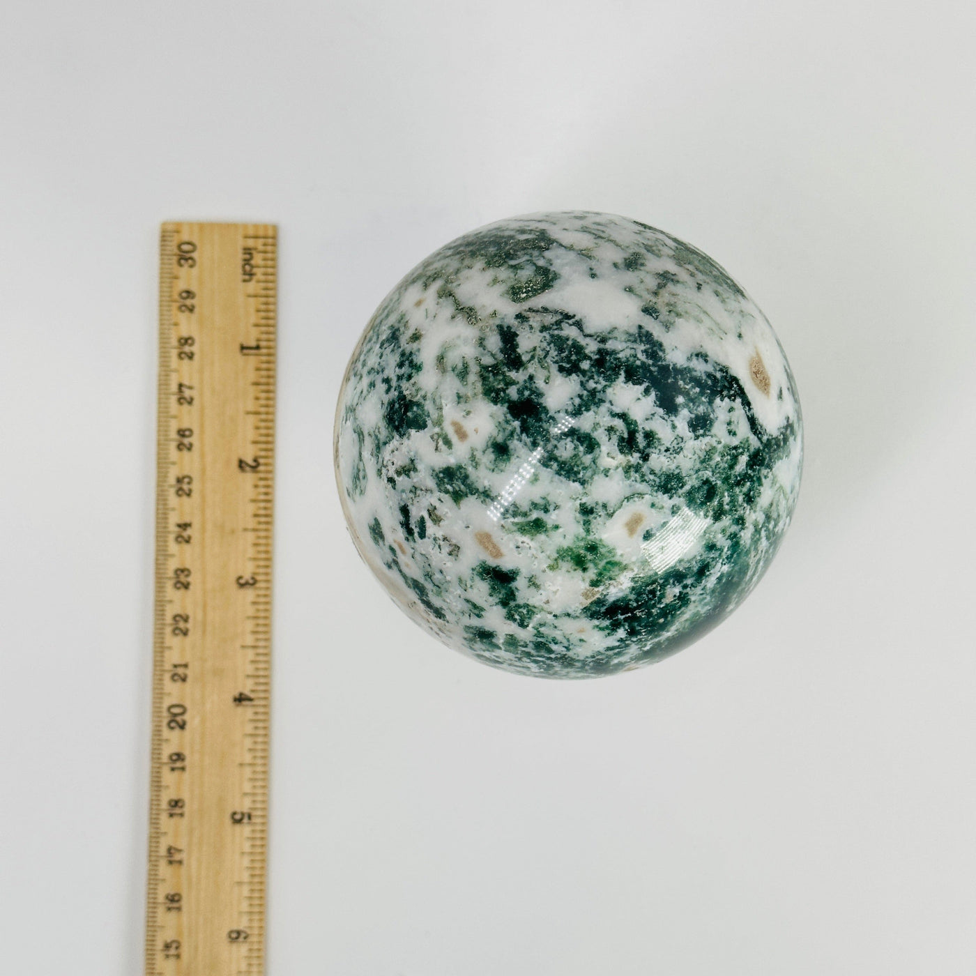 moss agate sphere next to a ruler for size reference