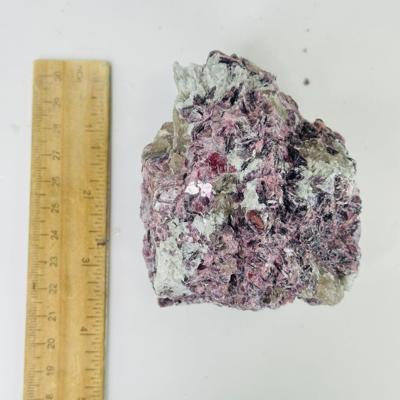 lepidolite cluster next to a ruler for size reference