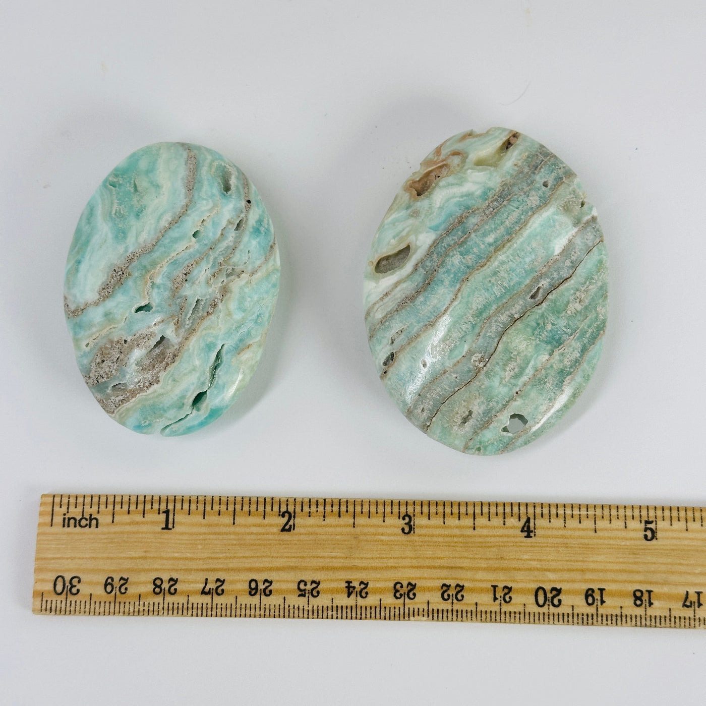 blue aragonite palm stones next to a ruler for size reference