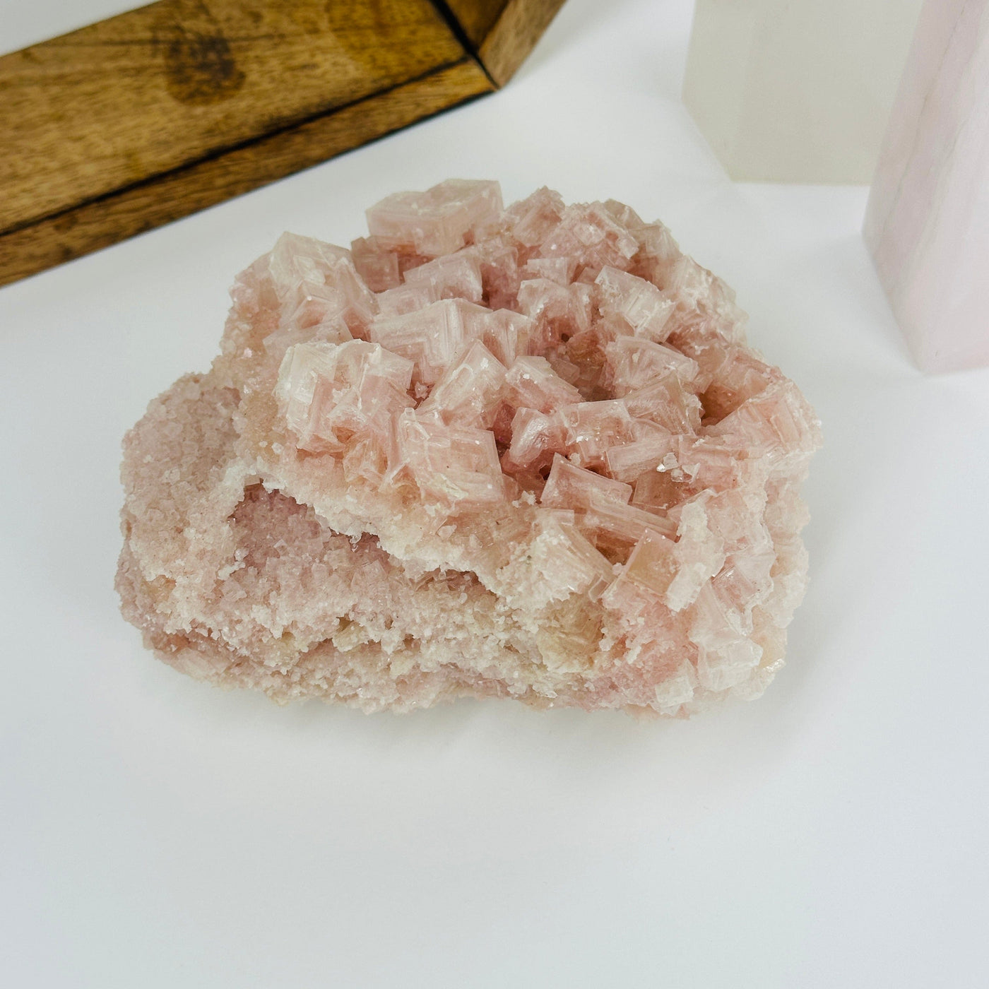 Pink halite cluster with decorations in the background