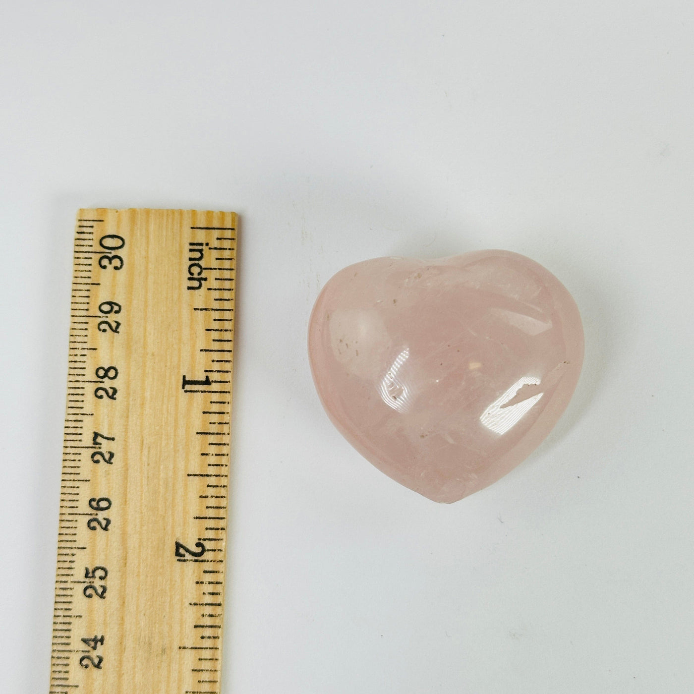 rose quartz heart next to a ruler for size reference