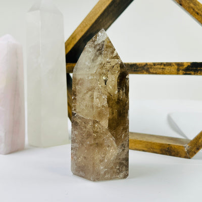 smokey quartz point with decorations in the background