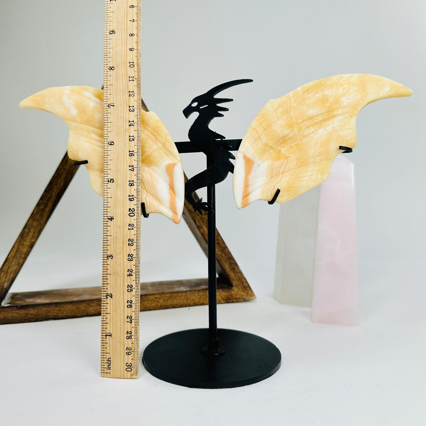 orange calcite dragon on metal stand next to a ruler for size reference