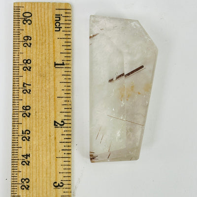 rutilated quartz next to a ruler for size reference