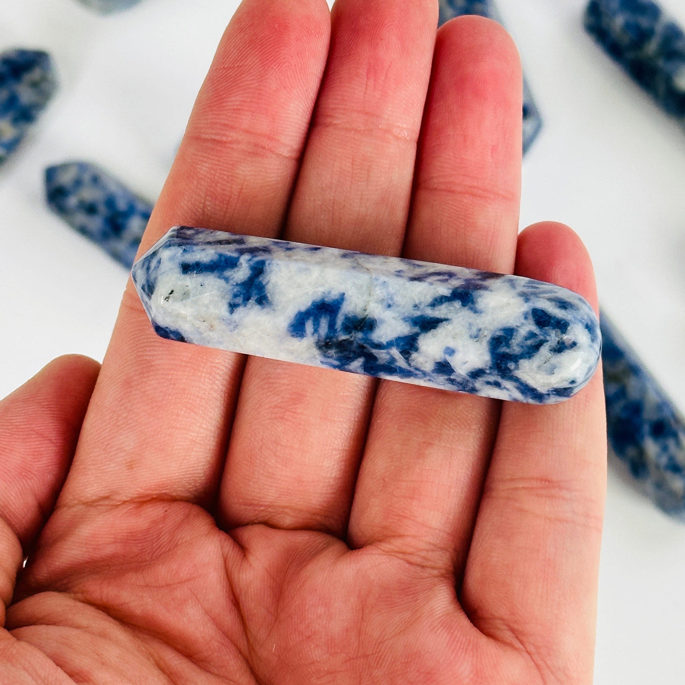 hand holding up sodalite massage wand with others in the background