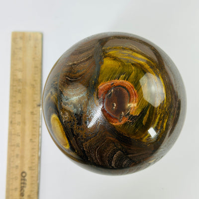 tigers eye sphere next to a ruler for size reference