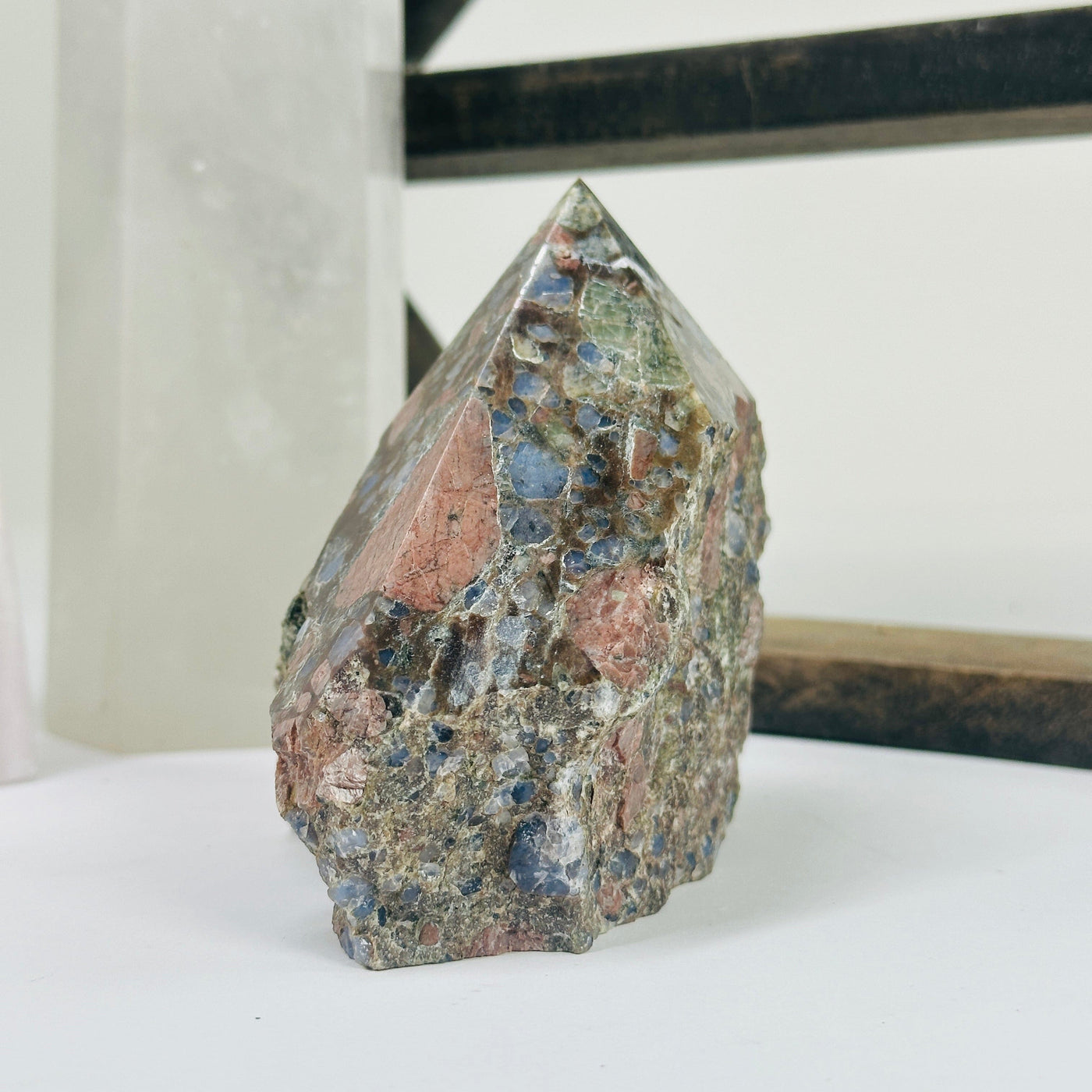rhyolite semi polished point with decorations in the background