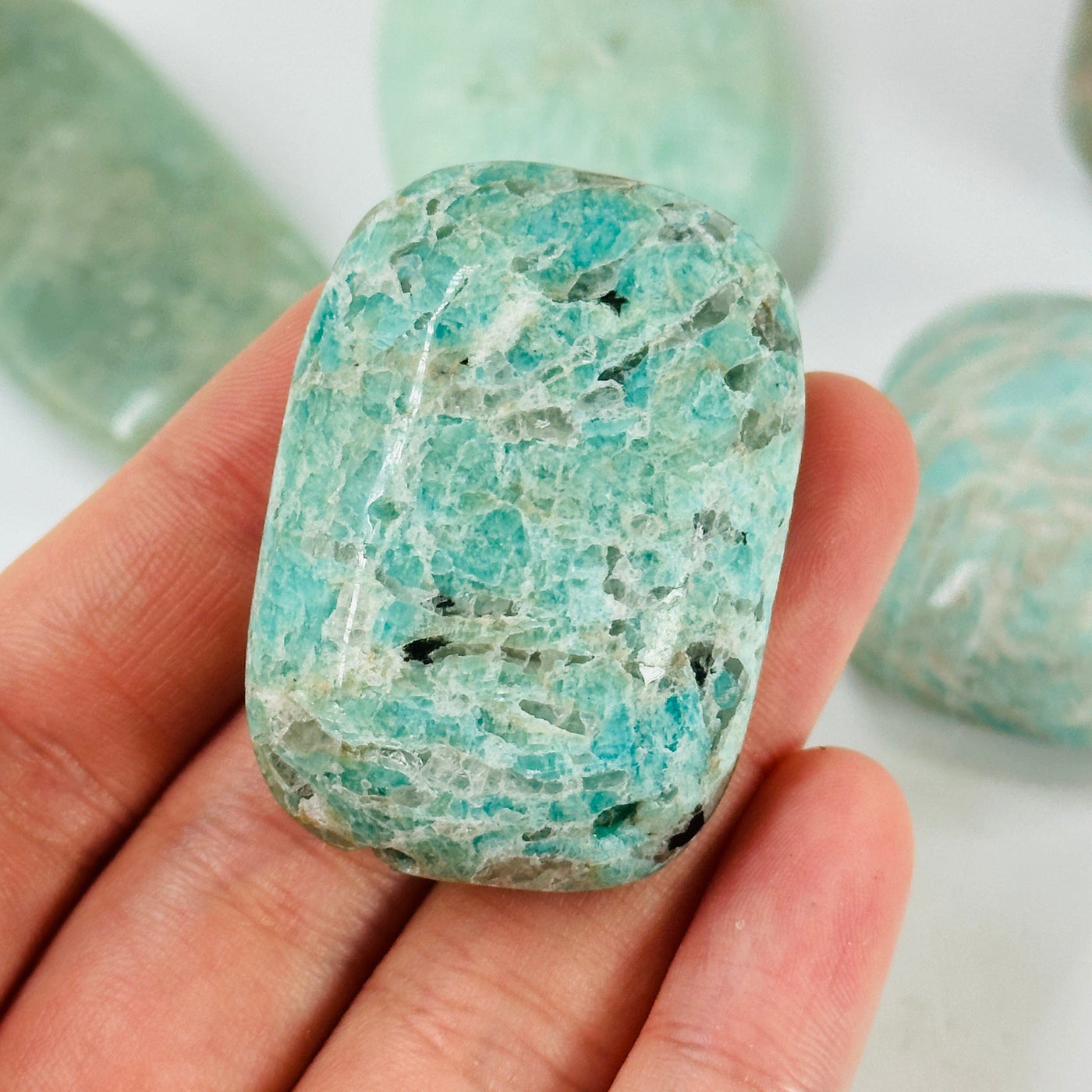 amazonite tumbled stone with decorations in the background