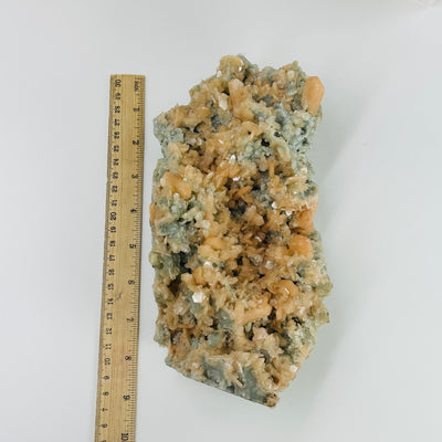 green apophyllite with peach stilbite next to a ruler for size reference