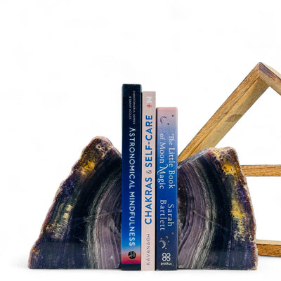 Fluorite Bookend with three books in between in front of a wood shelf with a white background.