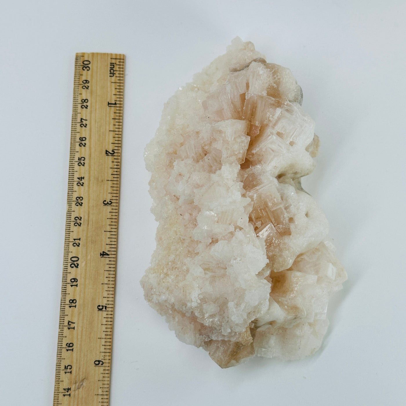 pink halite cluster next to a ruler for size reference