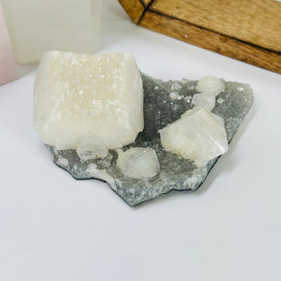 zeolite apophyllite on matrix with decorations in the background