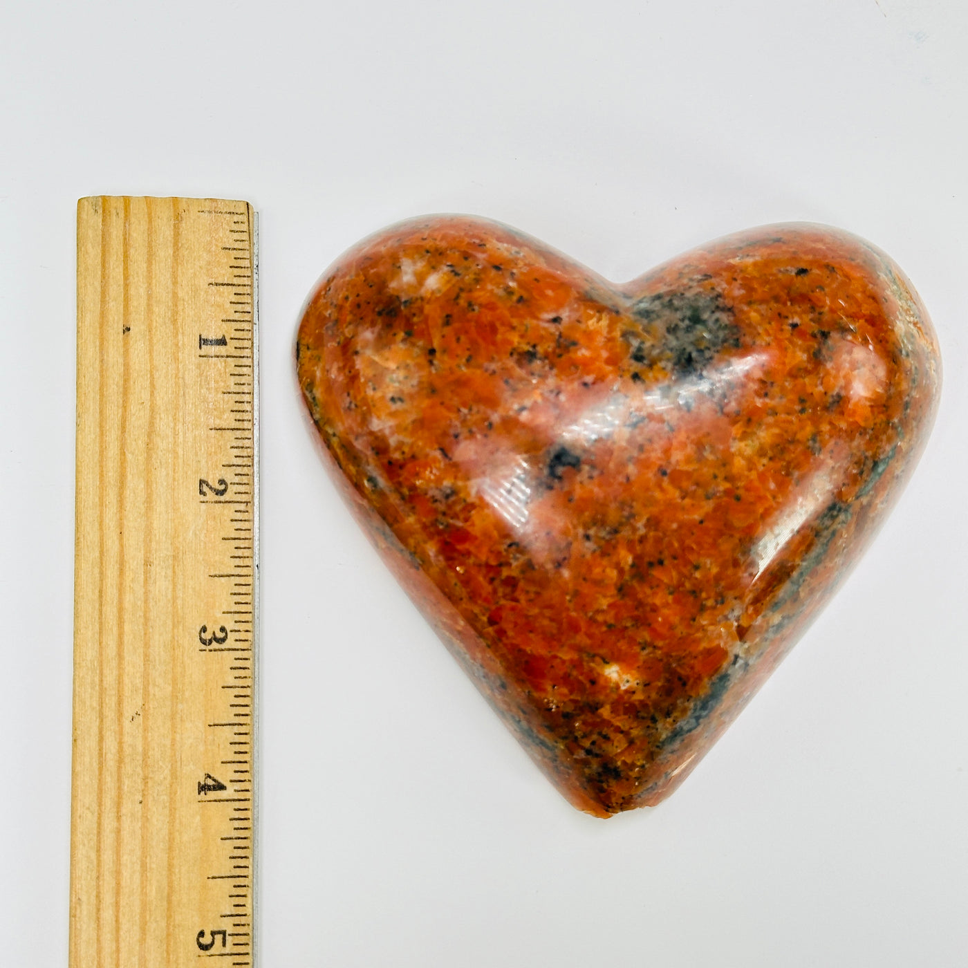 orchid calcite heart next to a ruler for size reference