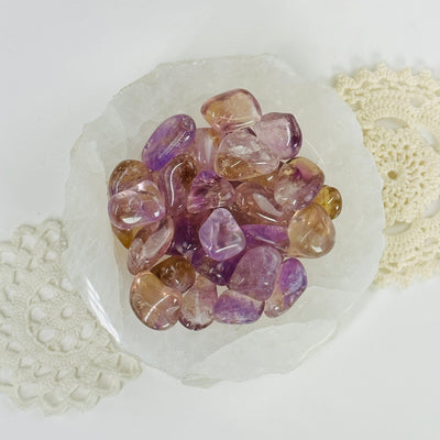 ametrine tumbled stones in a bowl with decorations in the background