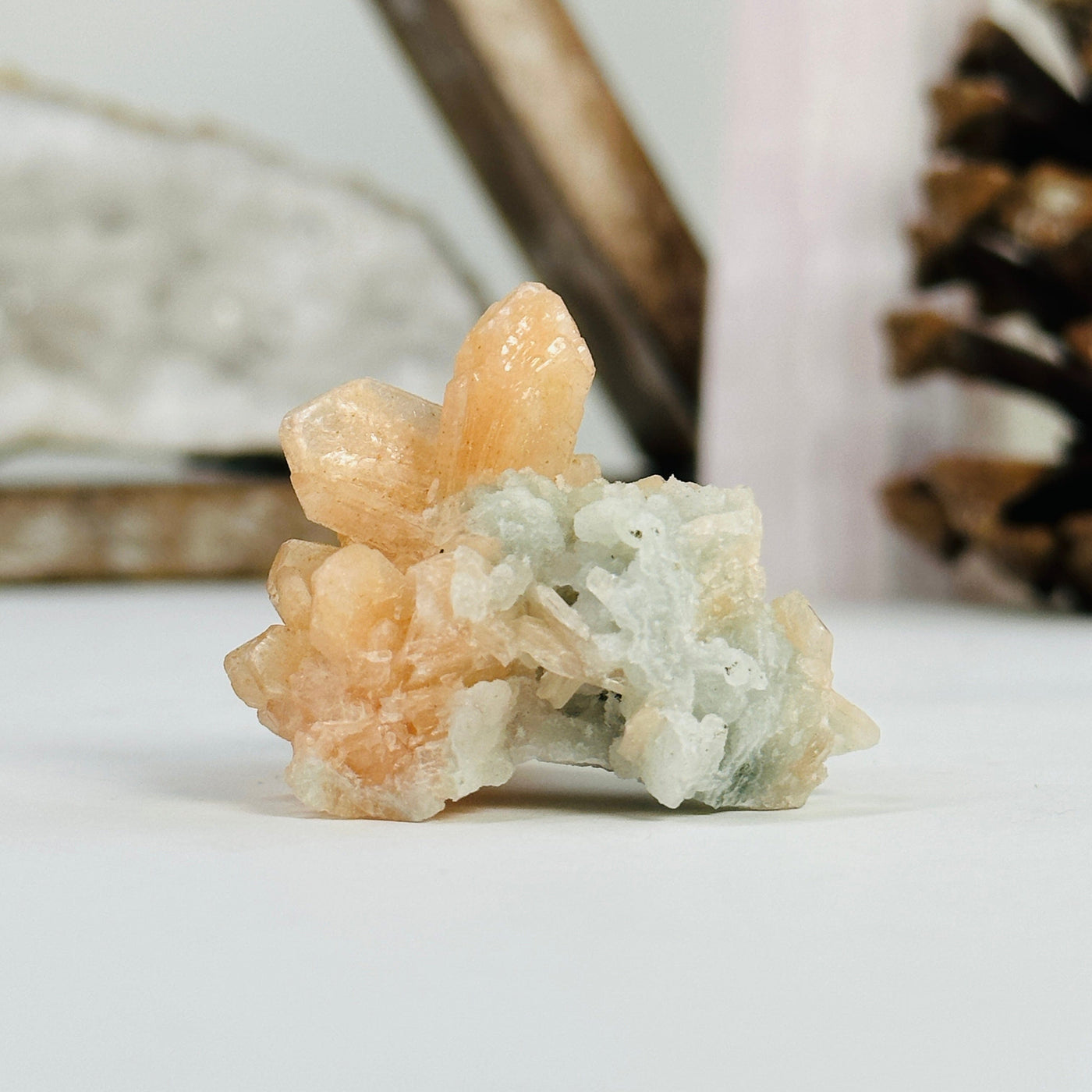 peach apophyllite cluster with decorations in the background