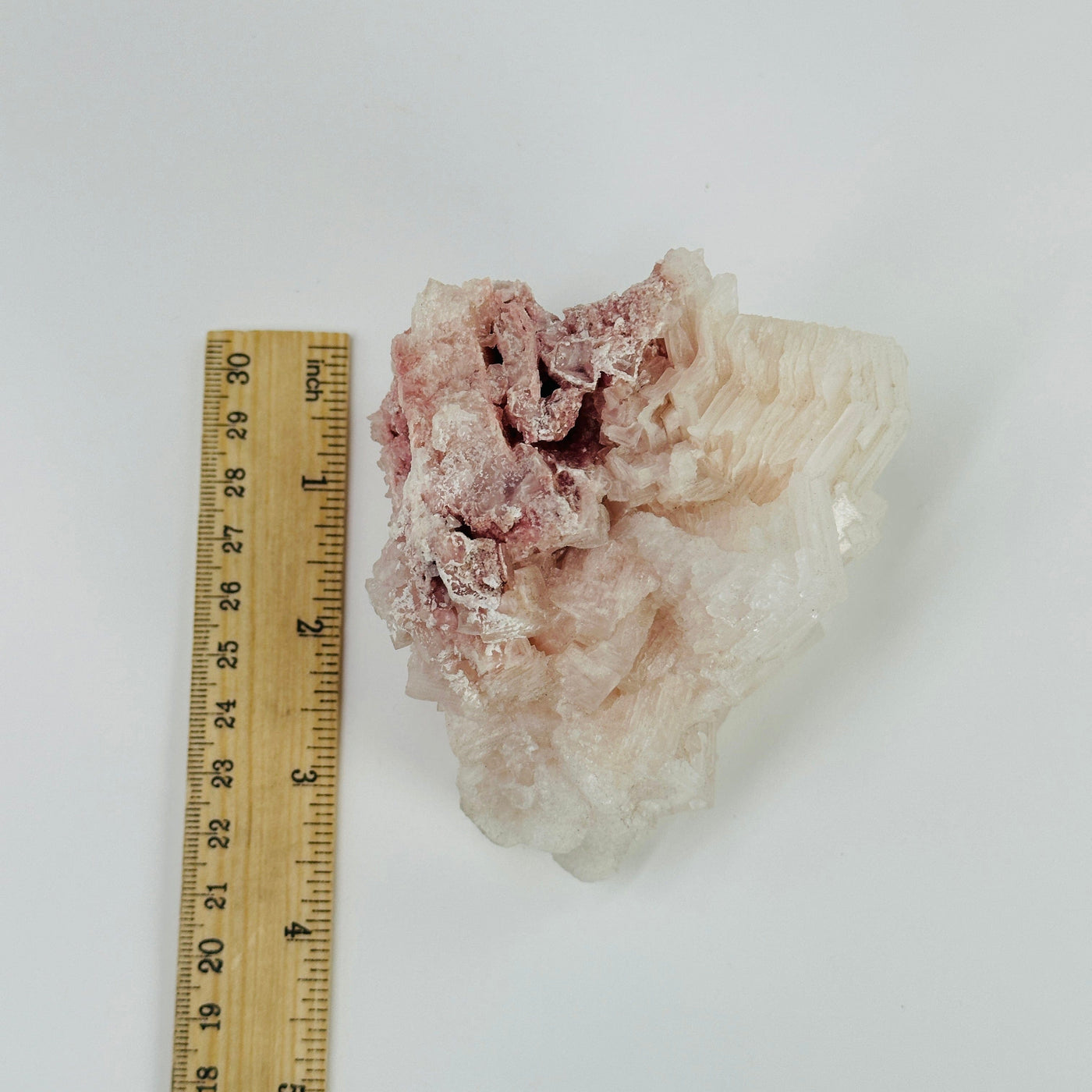 Pink halite cluster next to a ruler for size reference 