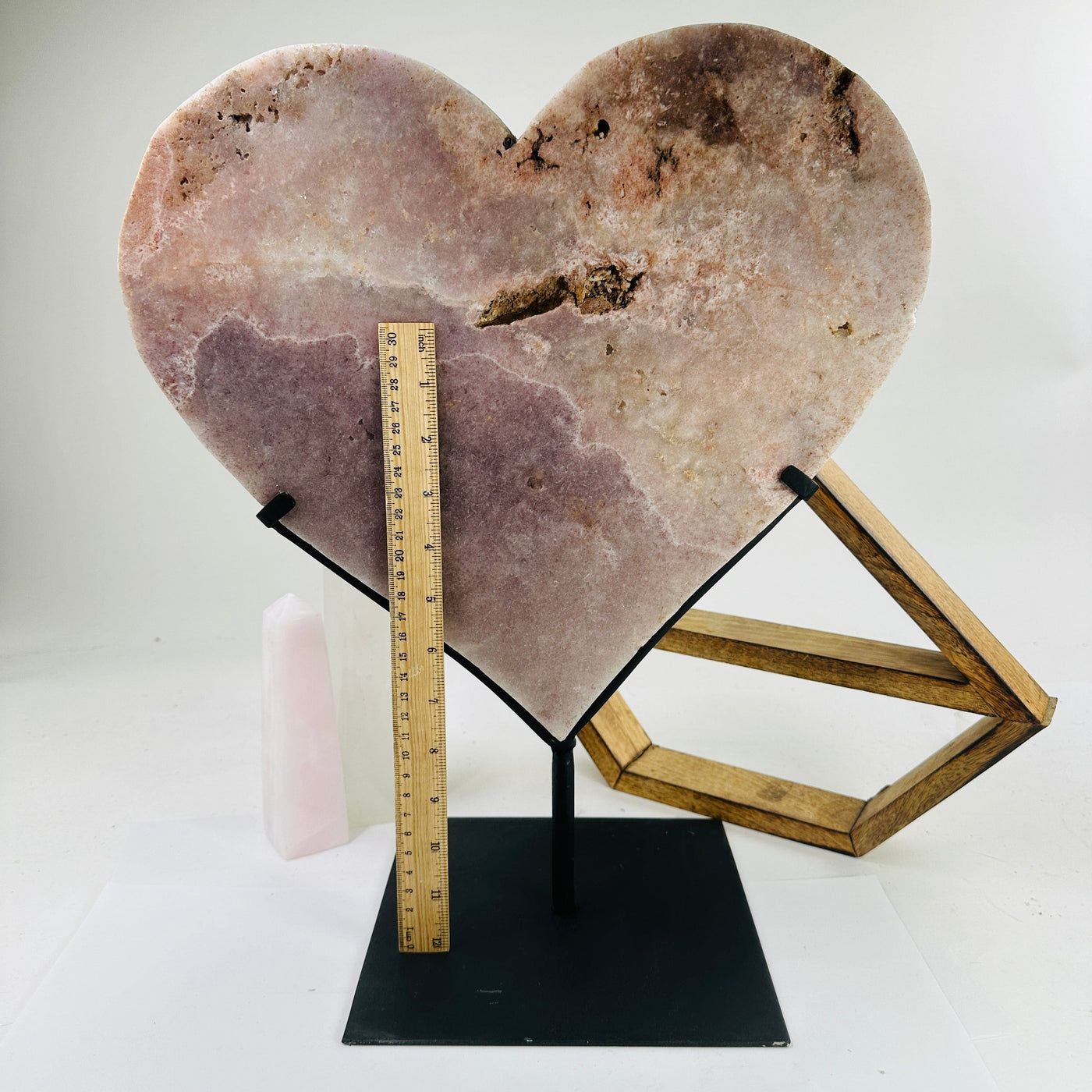 pink amethyst heart on stand next to a ruler for size reference