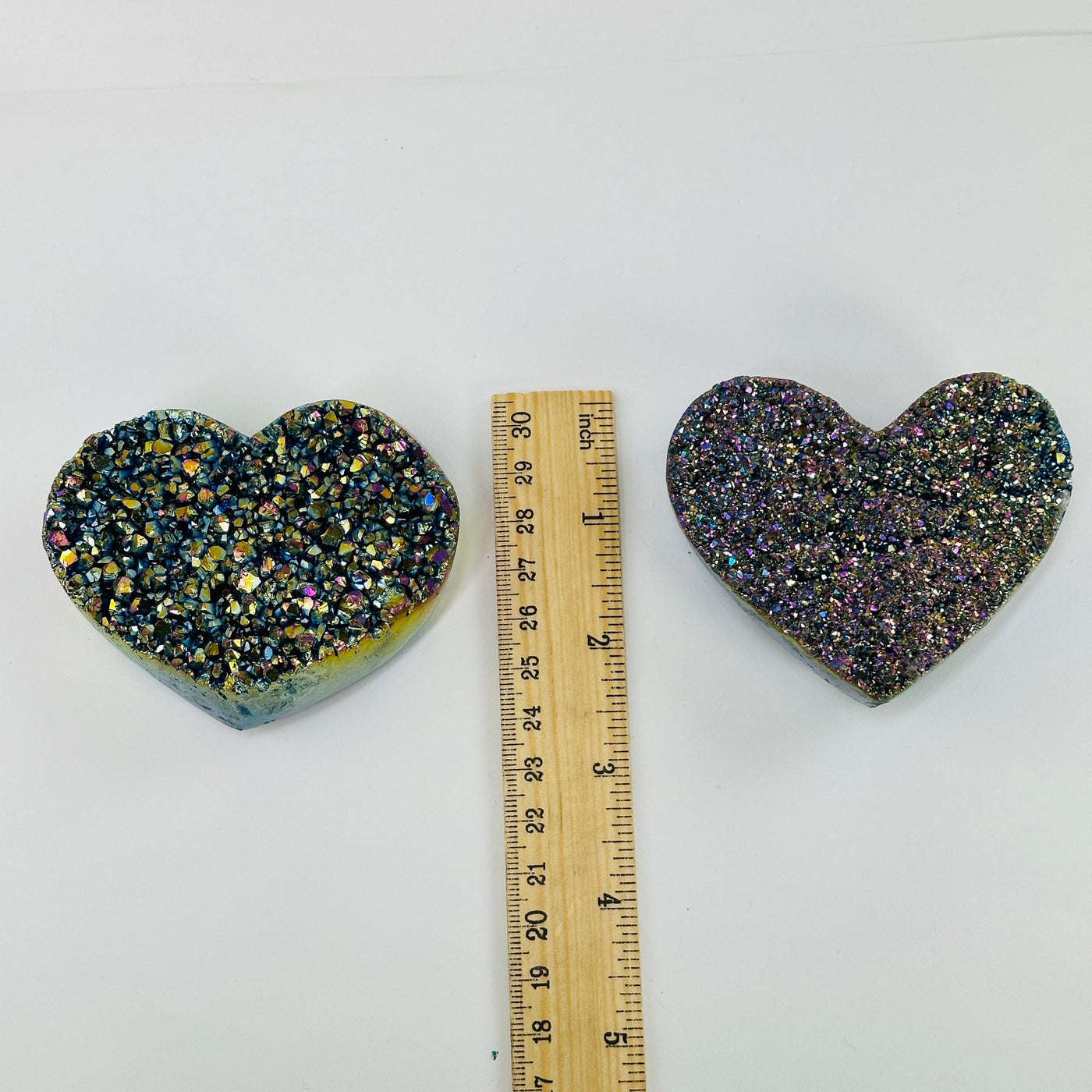 Rainbow titanium heart next to a ruler for size reference 