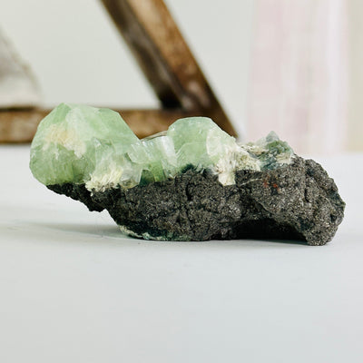  green apophyllite on matrix cluster with decorations in the background