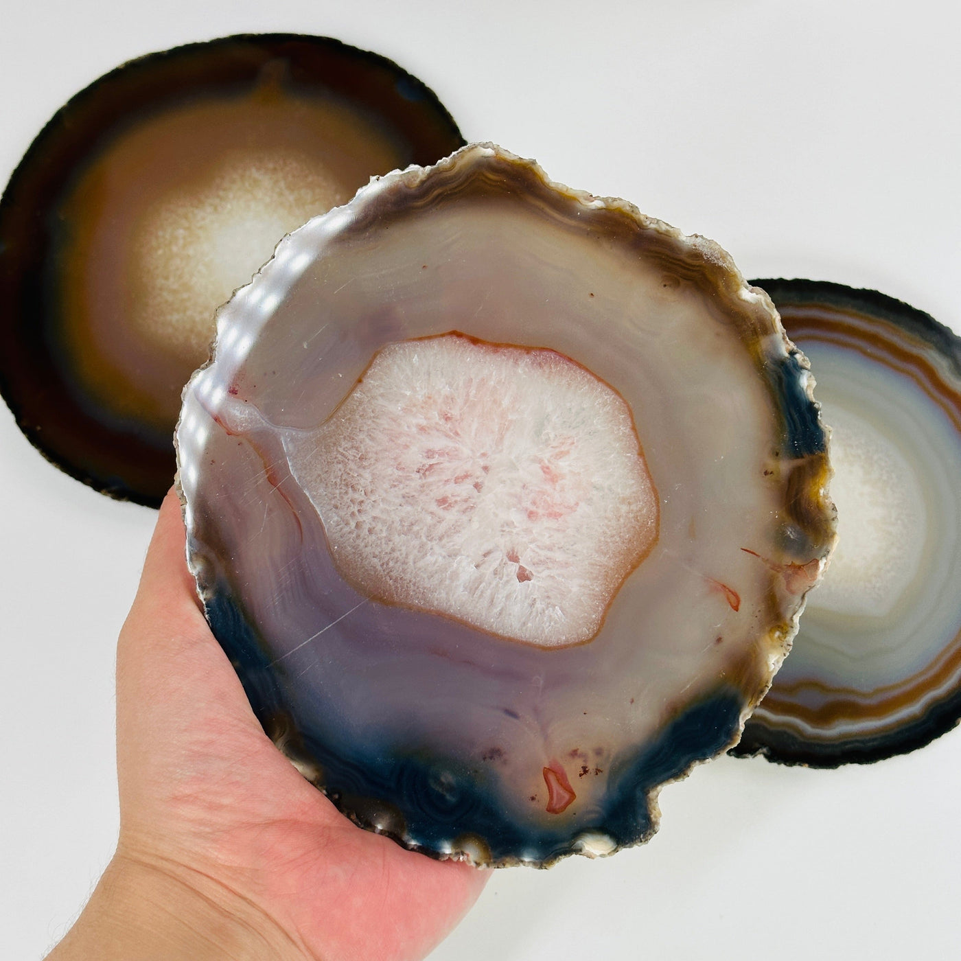 hand holding up agate slice with others in the background