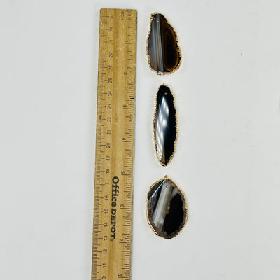 3 brown agate slices next to a ruler for size reference