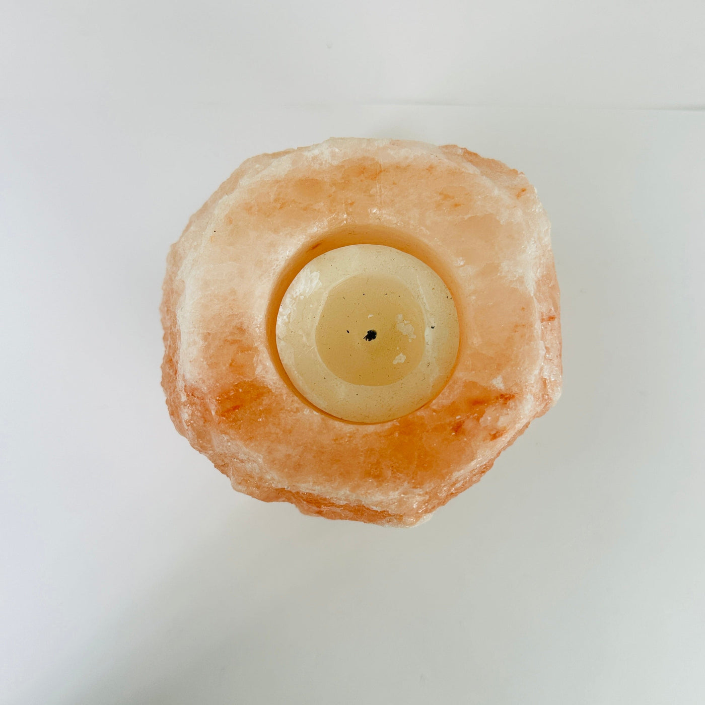 HIMALAYAN SALT CANDLE HOLDER WITH DECORATIONS IN THE BACKGROUND