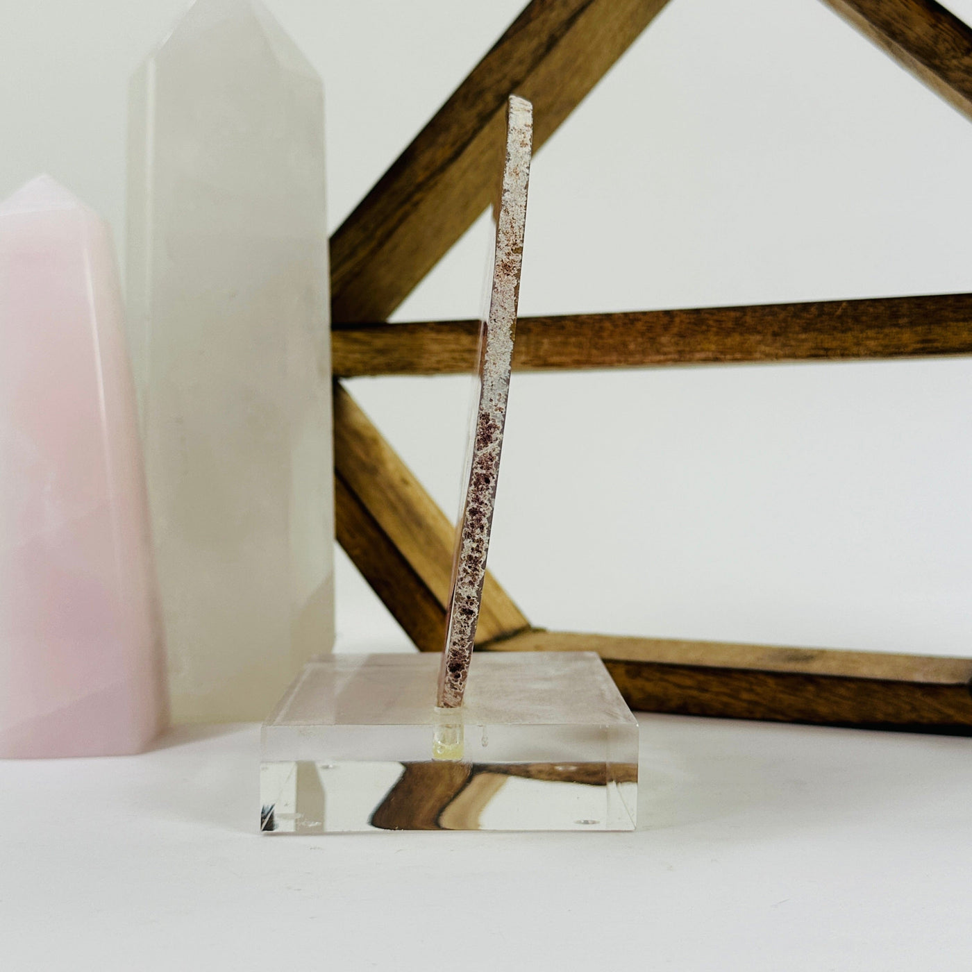 Pink agate slice on acrylic stand with decorations in the background