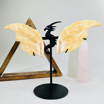 Orange calcite dragon on metal stand with decorations in the background