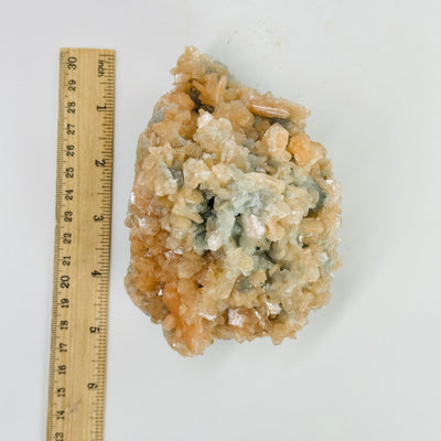 green apophyllite with peach stilbite next to a ruler for size reference