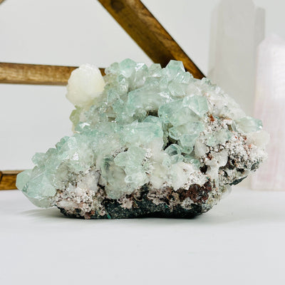 green apophyllite with stilbite with decorations in the background