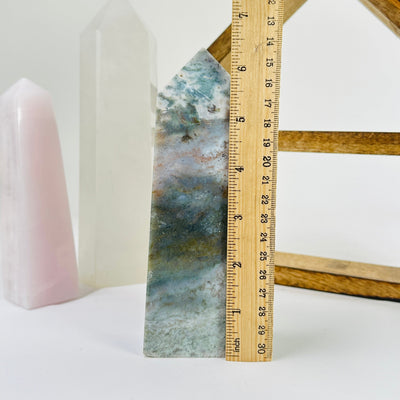 moss agate polished point next to a ruler for size reference
