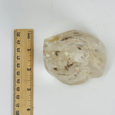 polished crystal quartz next to a ruler for size reference
