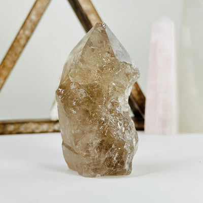 smoky quartz semi polished point with decorations in the background