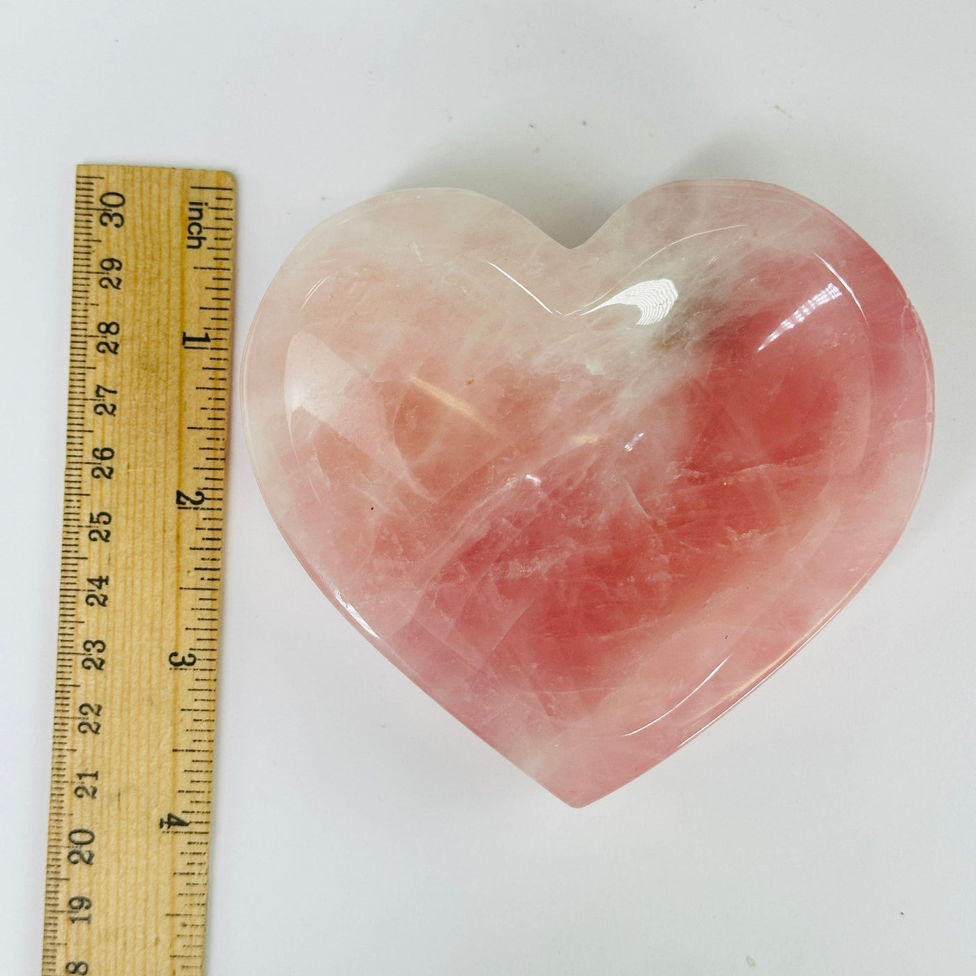 rose quartz heart bowl next to a ruler for size reference