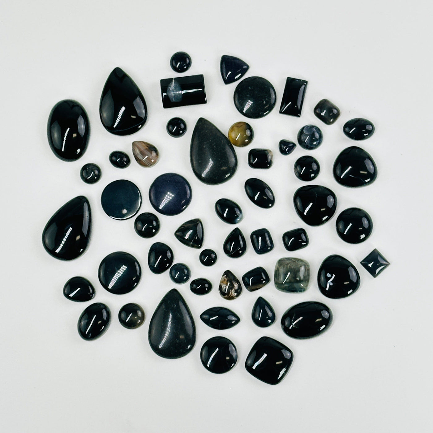 black stone cabochons scattered on white background